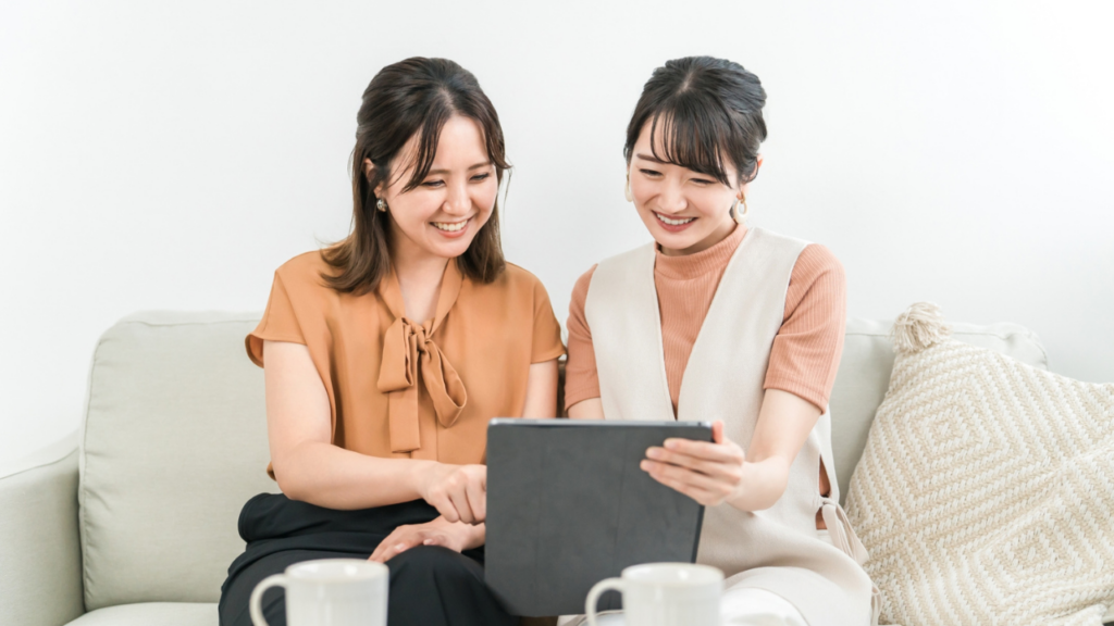 ソファでアイパッドを見る女性2人