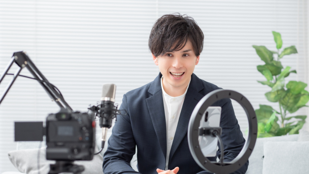 ライトやマイクを前にスマホで撮影する男性