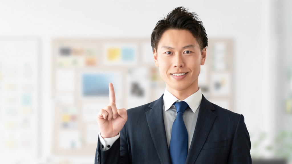 人差し指を立てるスーツ姿の男性