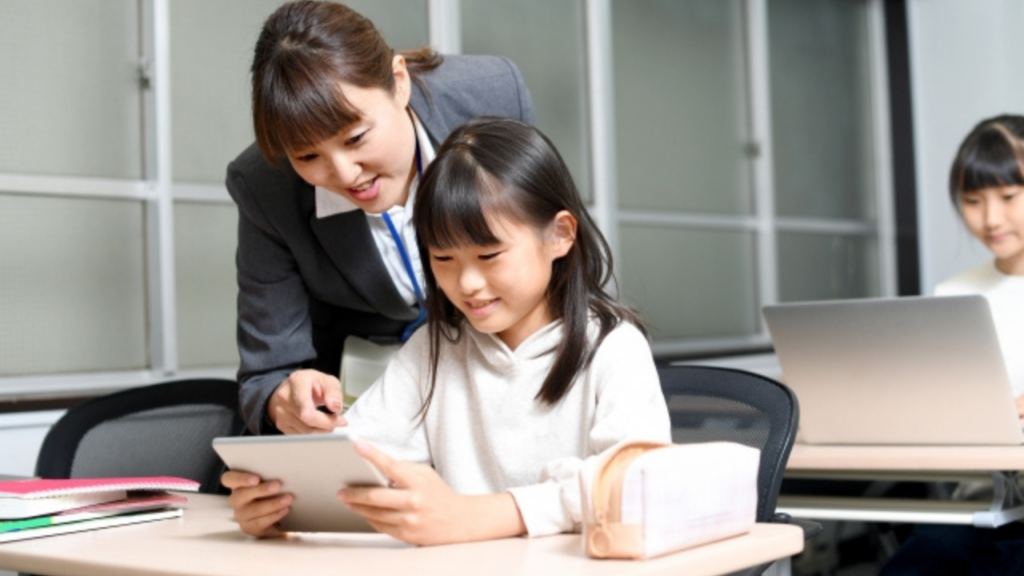 タブレッドを指差し女子児童に説明する女性教師