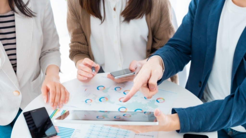 グラフやタブレットを見ながら話し合う3人