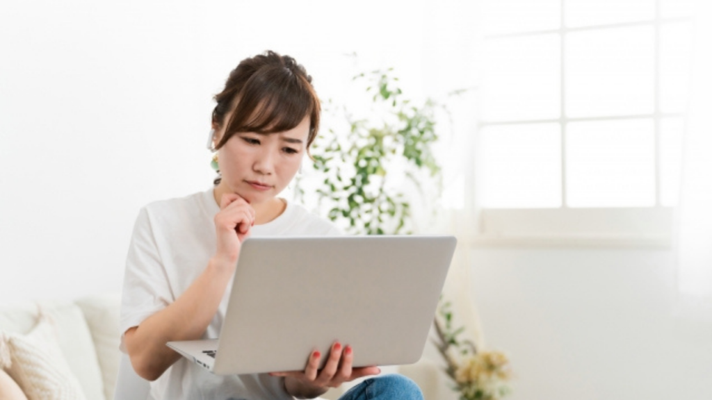 パソコンを開いて悩む女性