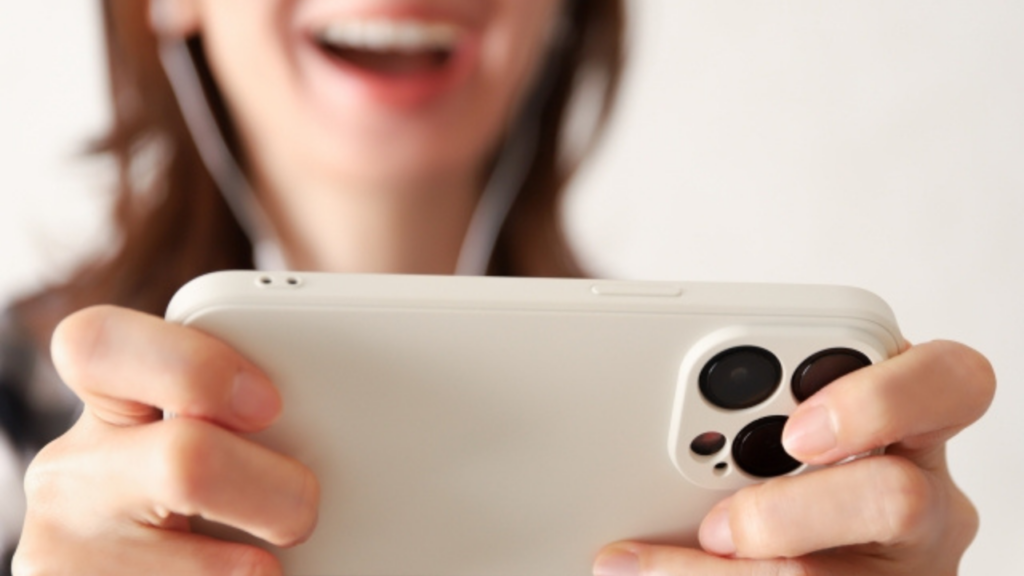 イヤホンをしてスマホを横向きに見る女性