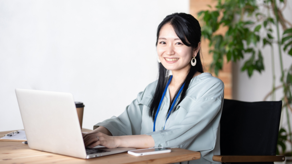 パソコンのキーボードの上に手を置きこちらを見る女性