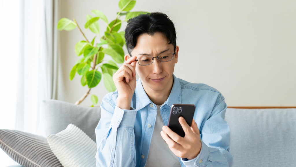 スマホを見るメガネをかけた男性