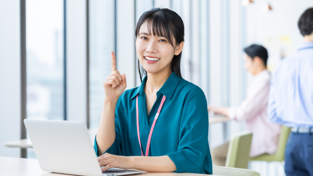 パソコンの前で人差し指を立てる女性